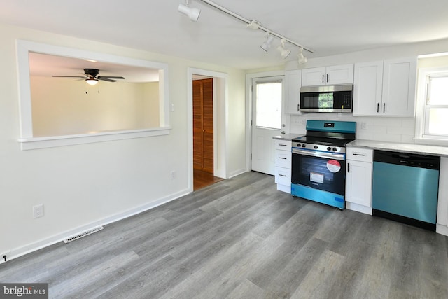 kitchen with plenty of natural light, rail lighting, wood-type flooring, and appliances with stainless steel finishes