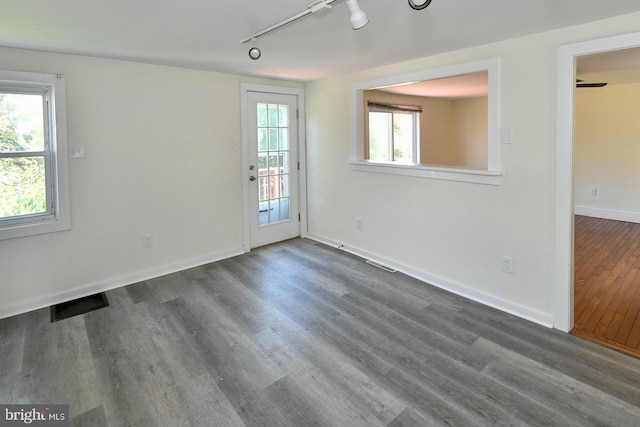 spare room featuring track lighting and dark hardwood / wood-style floors