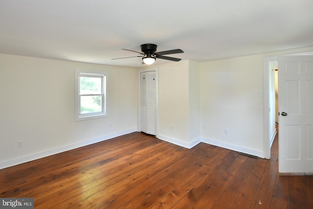 empty room with dark hardwood / wood-style flooring and ceiling fan