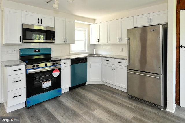 kitchen featuring dark hardwood / wood-style flooring, appliances with stainless steel finishes, sink, decorative backsplash, and white cabinets