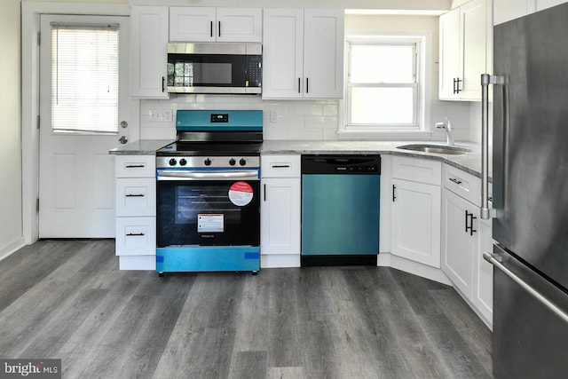 kitchen with light stone countertops, appliances with stainless steel finishes, dark wood-type flooring, sink, and white cabinets