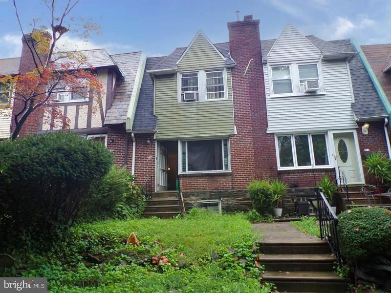 rear view of house featuring brick siding and a chimney