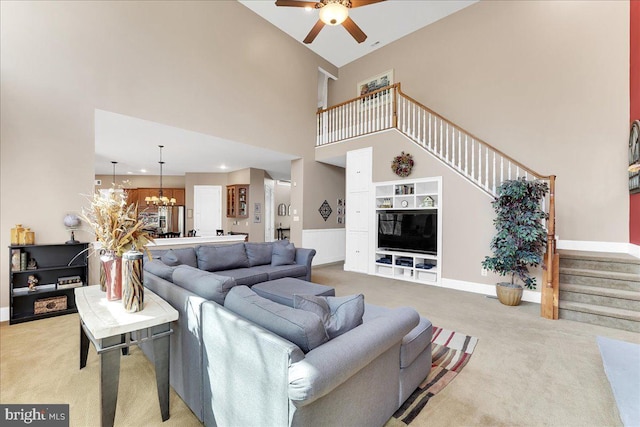 living room featuring carpet floors, ceiling fan with notable chandelier, and a high ceiling