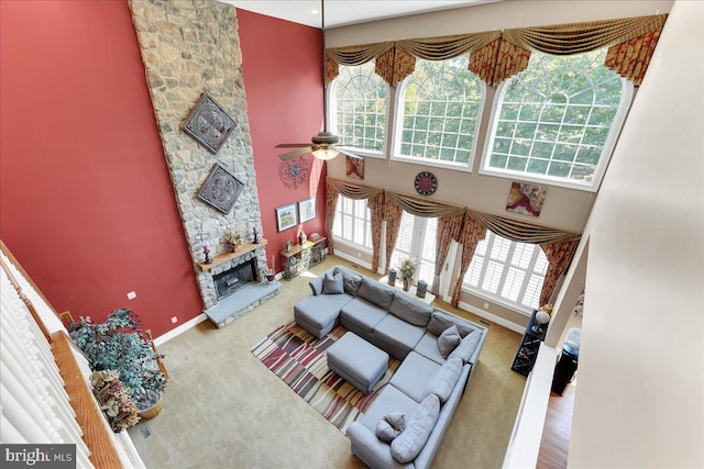 living room featuring ceiling fan, a fireplace, a towering ceiling, and carpet