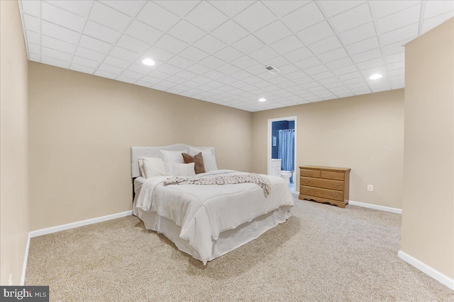 bedroom with a drop ceiling and light colored carpet