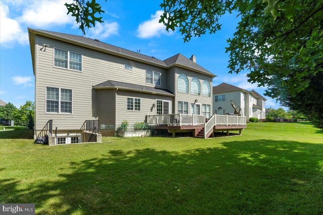 rear view of house with a deck and a yard