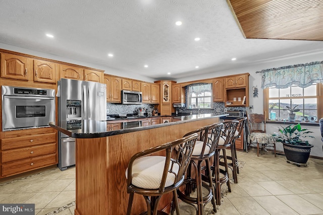 kitchen featuring appliances with stainless steel finishes, dark countertops, a center island, and a kitchen breakfast bar