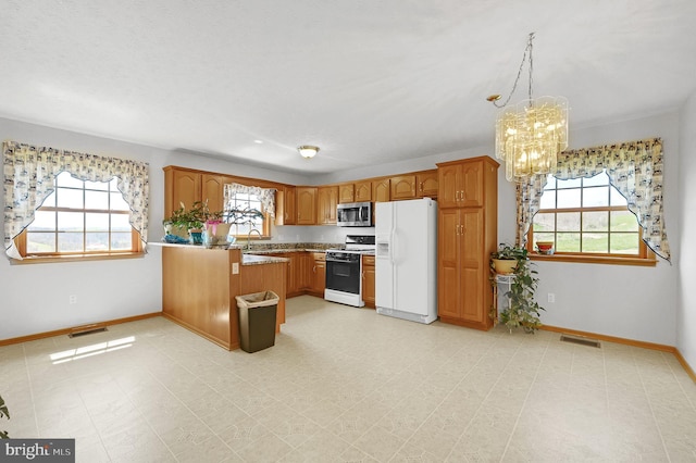 kitchen featuring white appliances, brown cabinets, a peninsula, light countertops, and pendant lighting