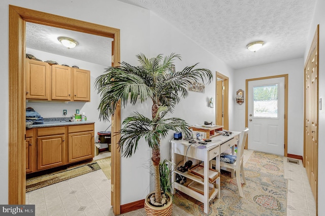 interior space featuring light floors, visible vents, a textured ceiling, and baseboards