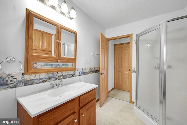 full bathroom with a stall shower, vanity, and a textured ceiling