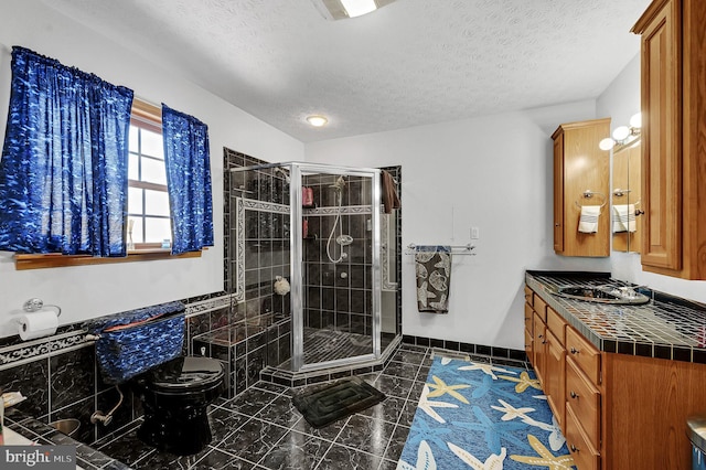 full bath with a shower stall, vanity, a textured ceiling, and tile patterned floors