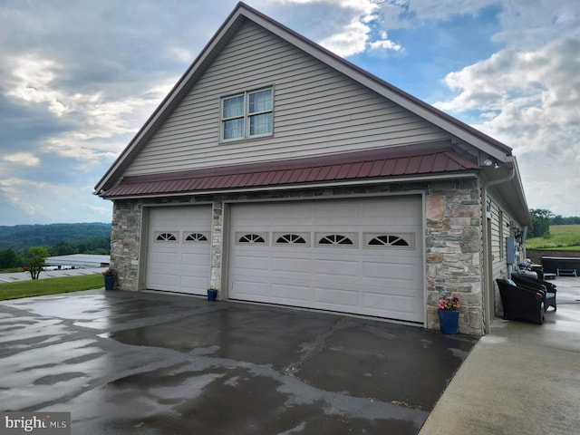 view of home's exterior featuring a garage, stone siding, and metal roof