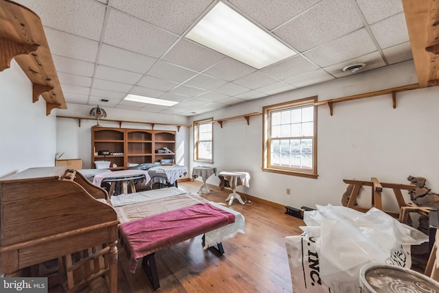 bedroom featuring a paneled ceiling, visible vents, baseboards, and wood finished floors