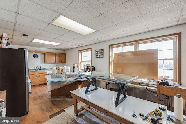 interior space with light wood-type flooring, visible vents, a paneled ceiling, and a sink