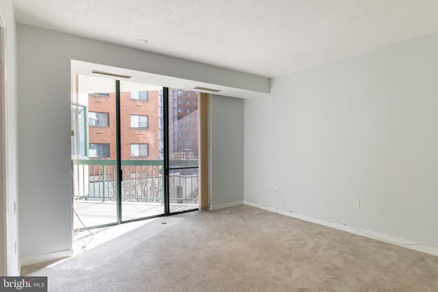 carpeted empty room featuring a textured ceiling