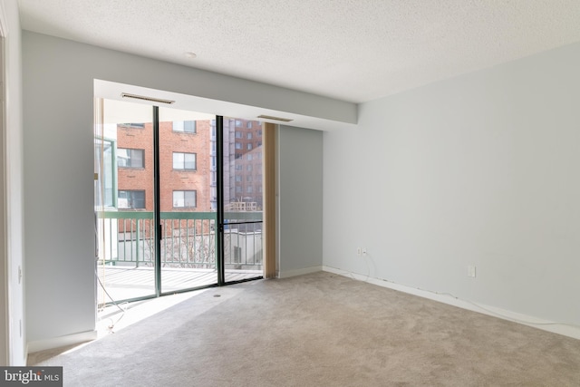 carpeted empty room with baseboards and a textured ceiling