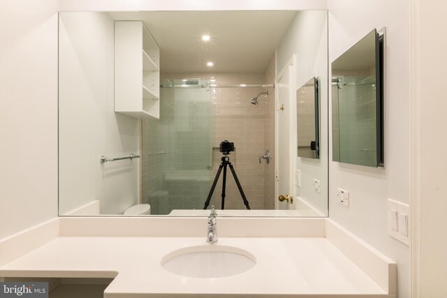 bathroom with vanity, toilet, and tiled shower