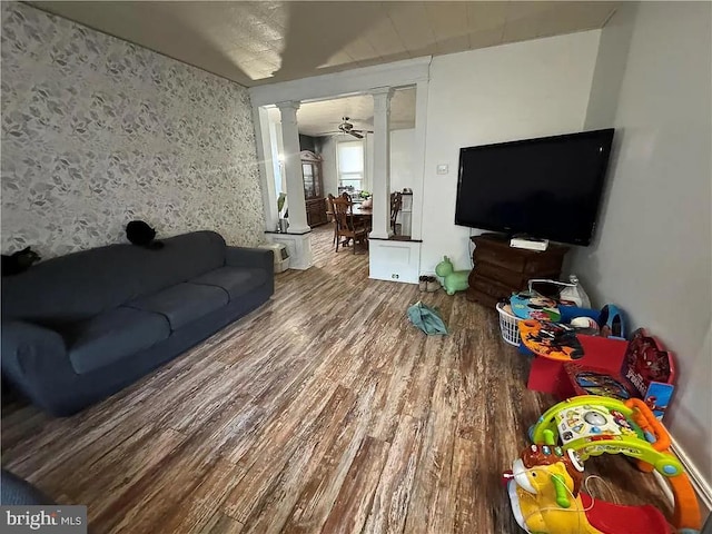 living room with wood-type flooring, ceiling fan, and decorative columns