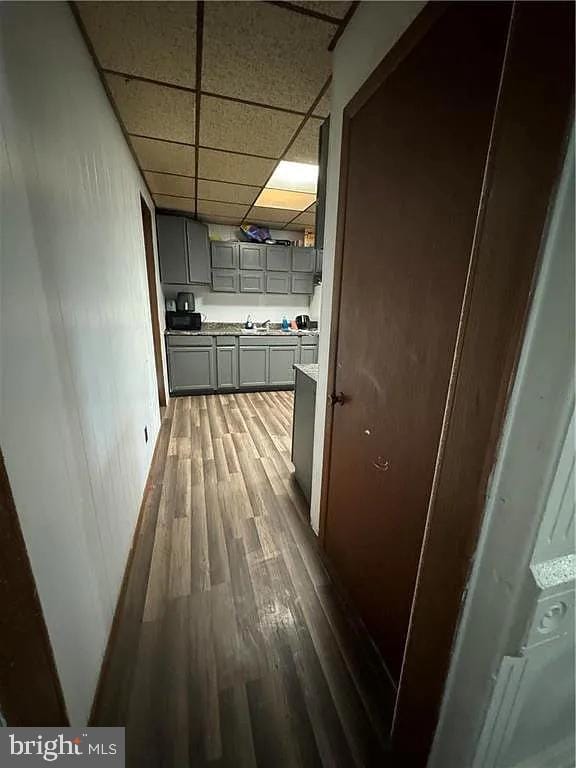 corridor with a paneled ceiling and hardwood / wood-style flooring