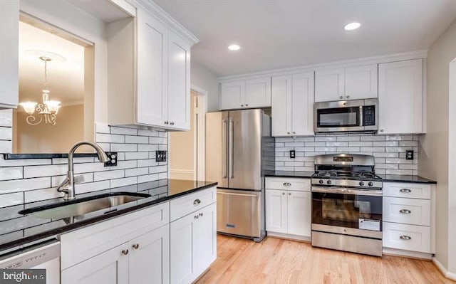 kitchen featuring light wood-type flooring, appliances with stainless steel finishes, tasteful backsplash, and white cabinetry