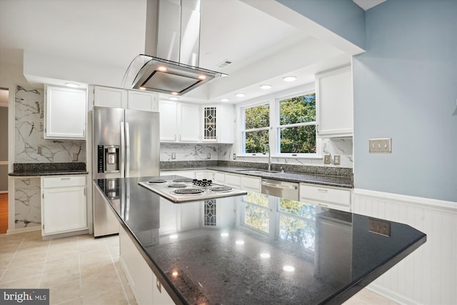 kitchen with a wainscoted wall, appliances with stainless steel finishes, island range hood, white cabinets, and a sink