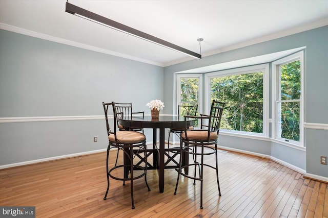 dining area with light wood-type flooring, baseboards, and crown molding