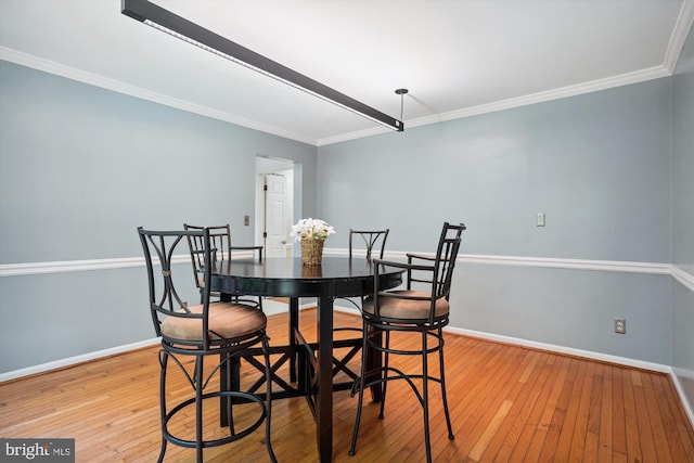 dining area with baseboards, light wood-style flooring, and ornamental molding