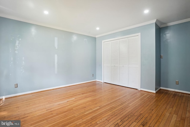 unfurnished bedroom featuring baseboards, wood-type flooring, a closet, and crown molding