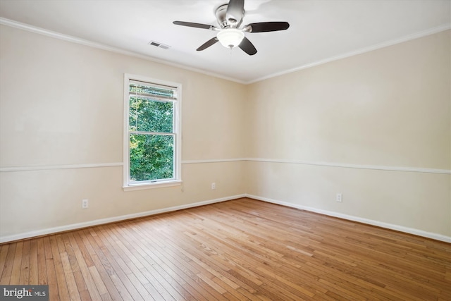 empty room featuring hardwood / wood-style flooring, baseboards, visible vents, and ornamental molding