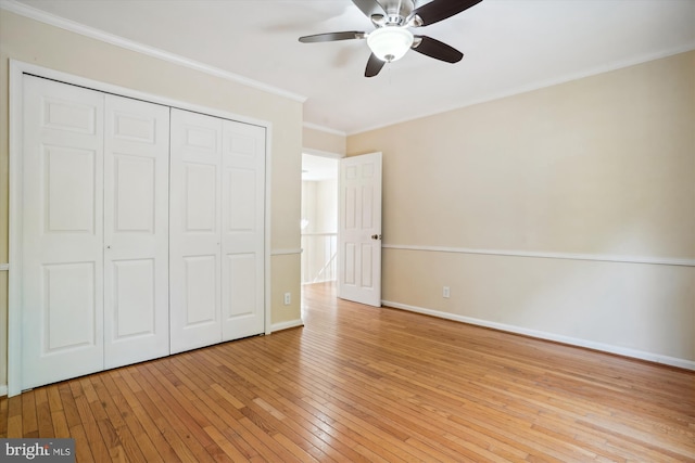 unfurnished bedroom with a closet, crown molding, light wood finished floors, baseboards, and ceiling fan