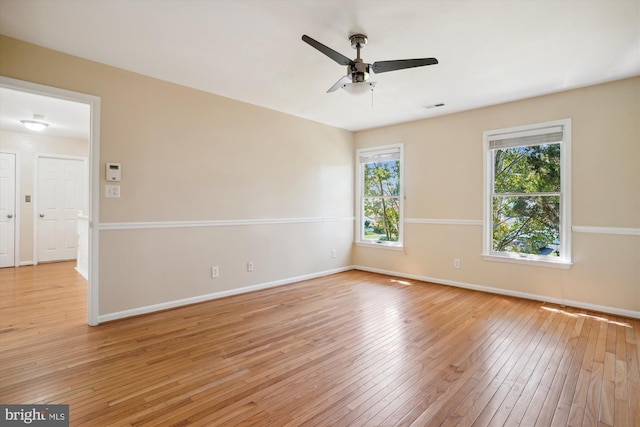 spare room featuring light wood-style flooring, a healthy amount of sunlight, visible vents, and baseboards