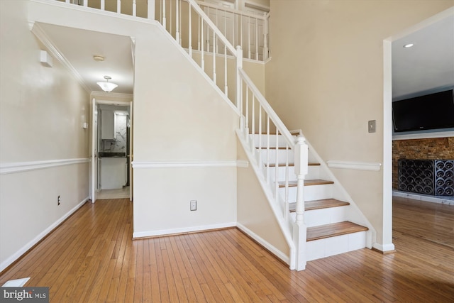 staircase featuring baseboards, wood-type flooring, and ornamental molding