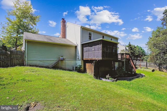 back of house featuring a lawn, stairs, fence, a sunroom, and a chimney