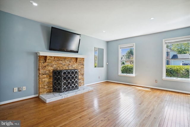 unfurnished living room with recessed lighting, a tile fireplace, baseboards, and hardwood / wood-style floors