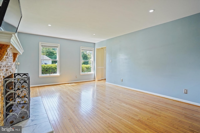 unfurnished living room with recessed lighting, baseboards, wood-type flooring, and a stone fireplace