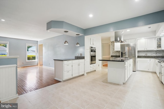 kitchen with island exhaust hood, tasteful backsplash, dark countertops, and white cabinetry