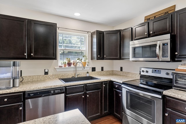 kitchen featuring hardwood / wood-style floors, stainless steel appliances, sink, and dark brown cabinetry