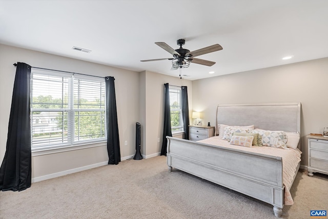 bedroom featuring multiple windows, ceiling fan, and light colored carpet