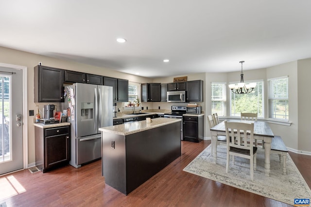 kitchen featuring appliances with stainless steel finishes, dark hardwood / wood-style floors, an inviting chandelier, and a healthy amount of sunlight