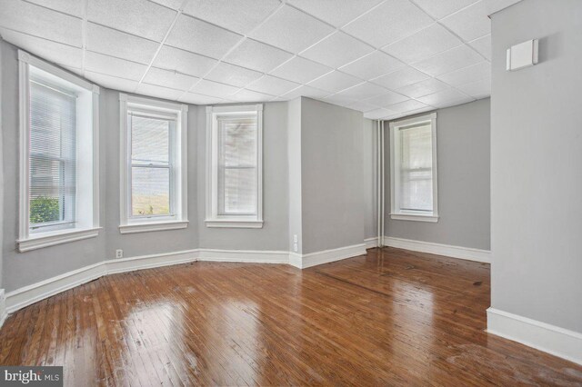 empty room with dark wood-type flooring and a paneled ceiling