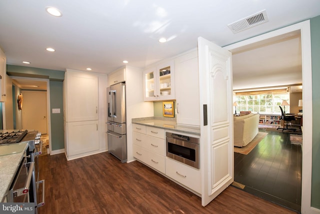 kitchen with white cabinets, appliances with stainless steel finishes, visible vents, and light stone countertops