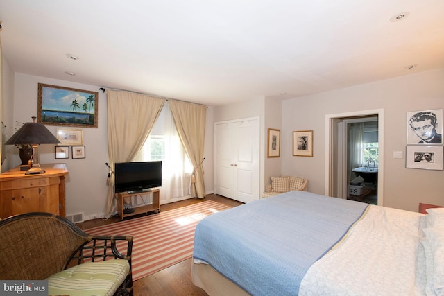 bedroom with a closet, multiple windows, wood finished floors, and visible vents