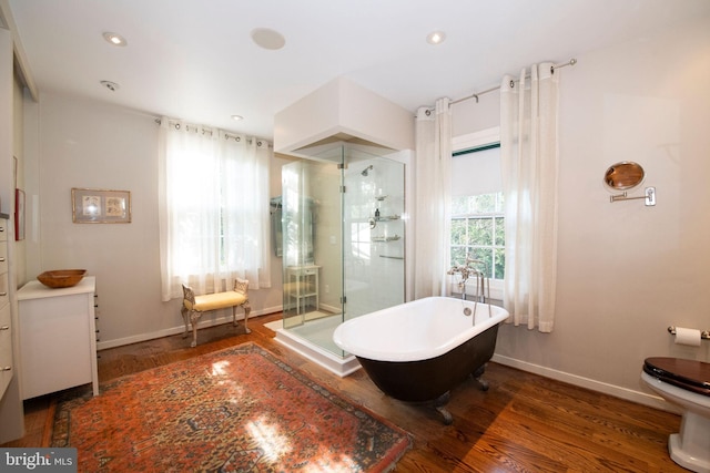 full bathroom featuring a stall shower, baseboards, toilet, wood finished floors, and a freestanding tub