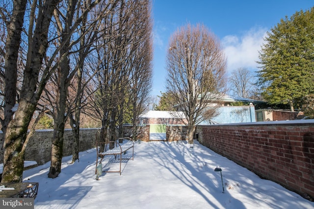 snowy yard with a patio area and fence