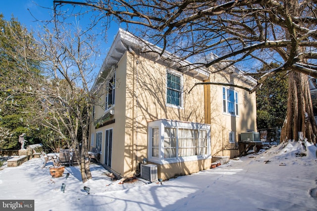 view of front of home with central AC, a patio, and stucco siding