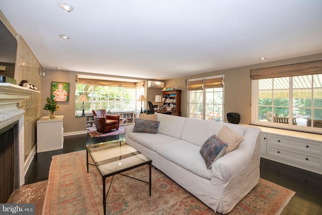 living room featuring an AC wall unit, dark wood-type flooring, a premium fireplace, and recessed lighting