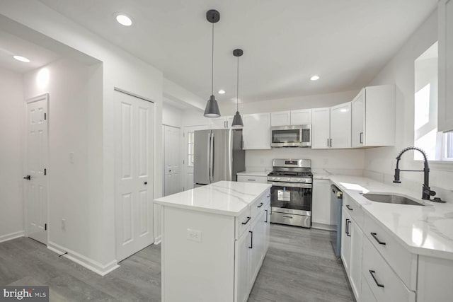 kitchen featuring sink, a kitchen island, hardwood / wood-style floors, stainless steel appliances, and decorative light fixtures