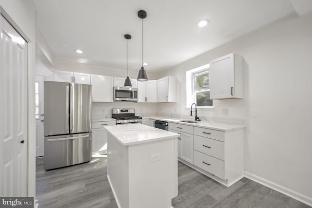 kitchen with a kitchen island, hanging light fixtures, stainless steel appliances, sink, and white cabinets