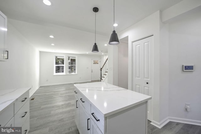 kitchen with dark wood-type flooring, hanging light fixtures, a kitchen island, and white cabinets