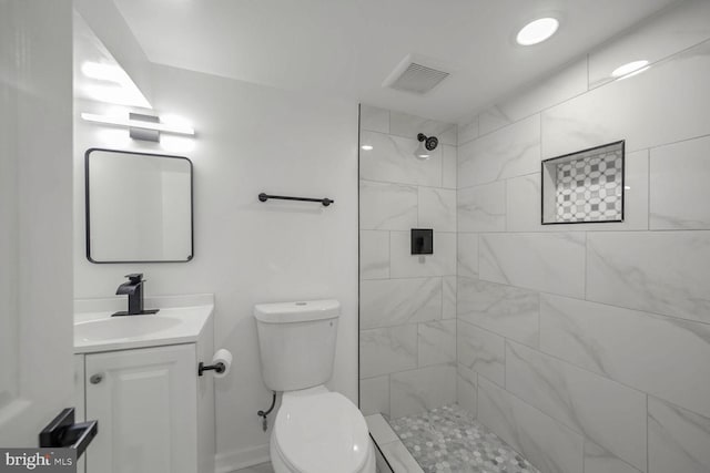 bathroom with toilet, vanity, and tiled shower